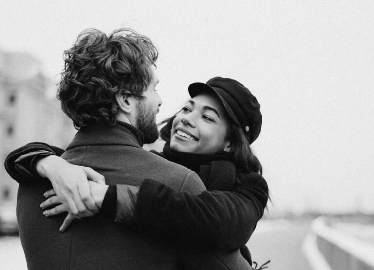 A happy couple warmly embracing on a snowy day, showcasing love and affection.