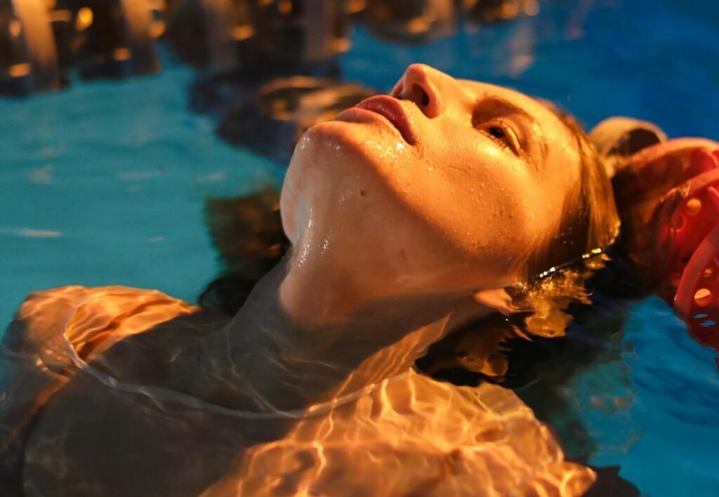 Close-up of a woman relaxing in a well-lit pool at night, showcasing serene ambiance.